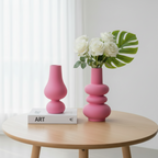 Image de deux vases roses en verre design posés sur une table en bois