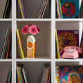 Photo vase bouteille de jus d'orange dans une bibliothèque à cases carrées blanche avec des vynilles et un téléphone rose