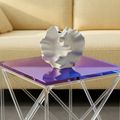 Photo du vase en ceramique hortensia posé sur une table en verre incandescent. Il y a un canape jaune derrière la table.
