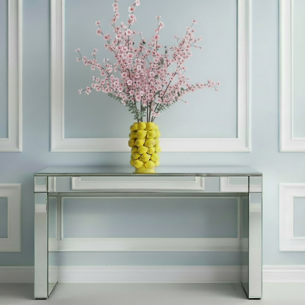 Photo du vase en ceramique citron compose de plusieurs citron. Il est posé sur une console en miroir devant un mur bleu avec des moulures blanches.