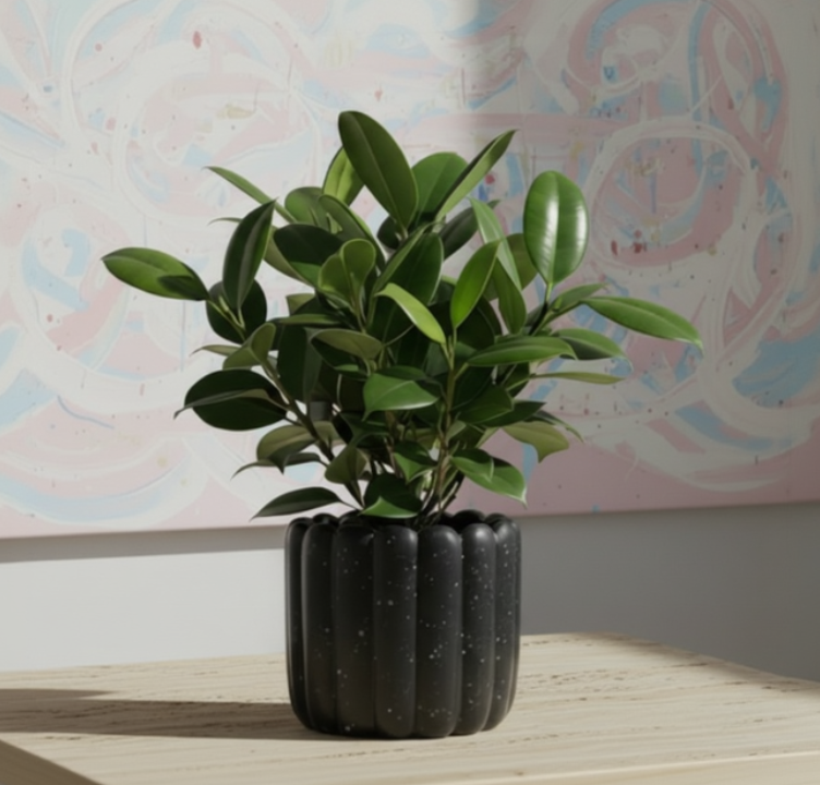 Photo de presentation du cache pot ficus noir en ceramique sur une table en travertin devant un tableau d'inspiration polok rose et bleu